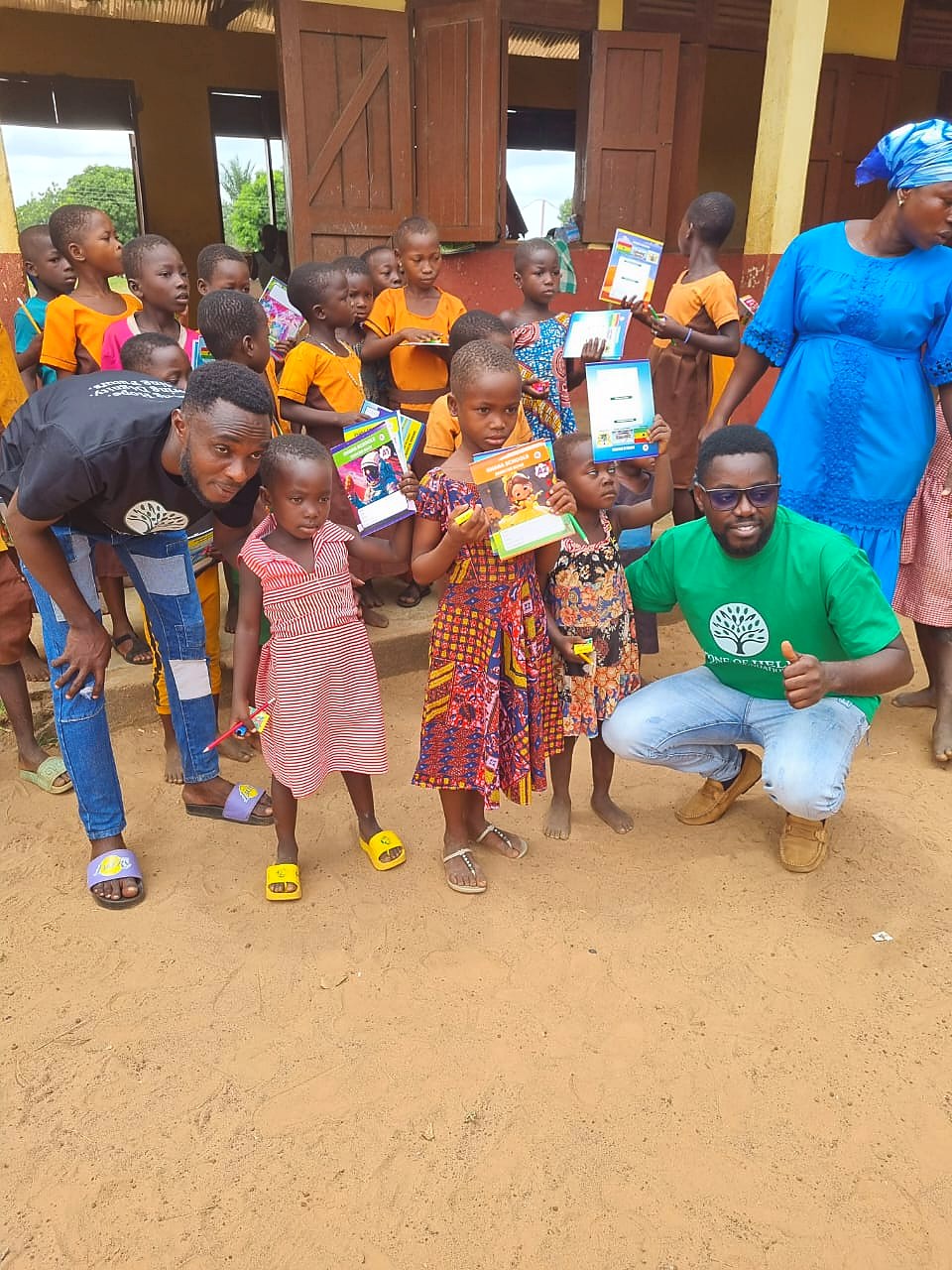 Students holding donated exercise books with outreach partners outside a school building